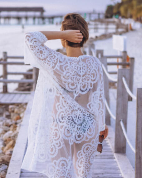 Sheer white lace cover-up with an intricate floral pattern over turquoise-colored swimwear.