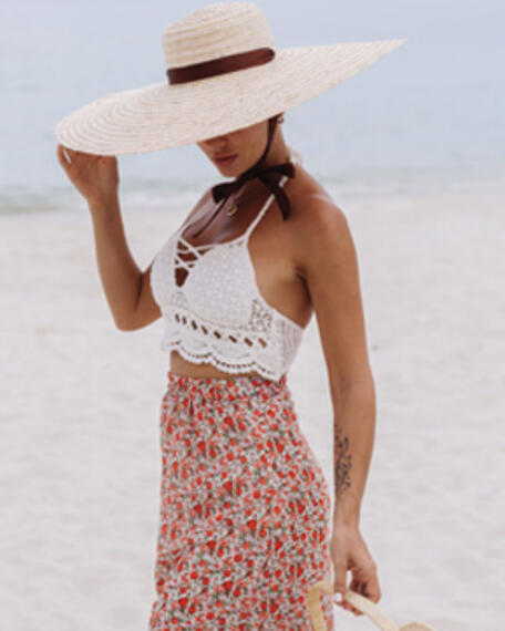 Wide brim sun hat and scalloped design halter-style top paired with a high-waisted skirt.